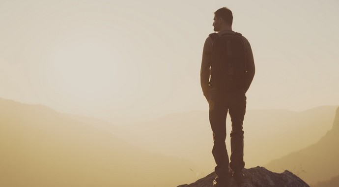 парень на вершине горы смотрит вдаль на рассвете